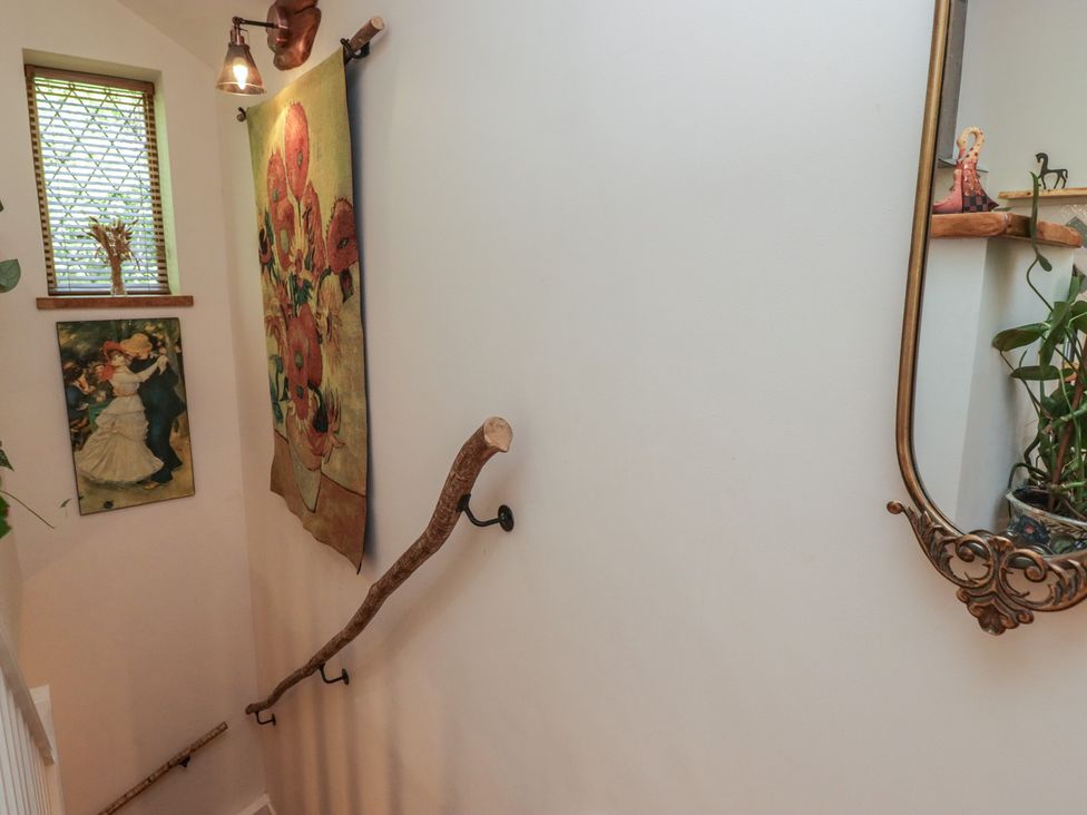 A staircase with a tapestry and paintings at Cân adar in Llangeinor