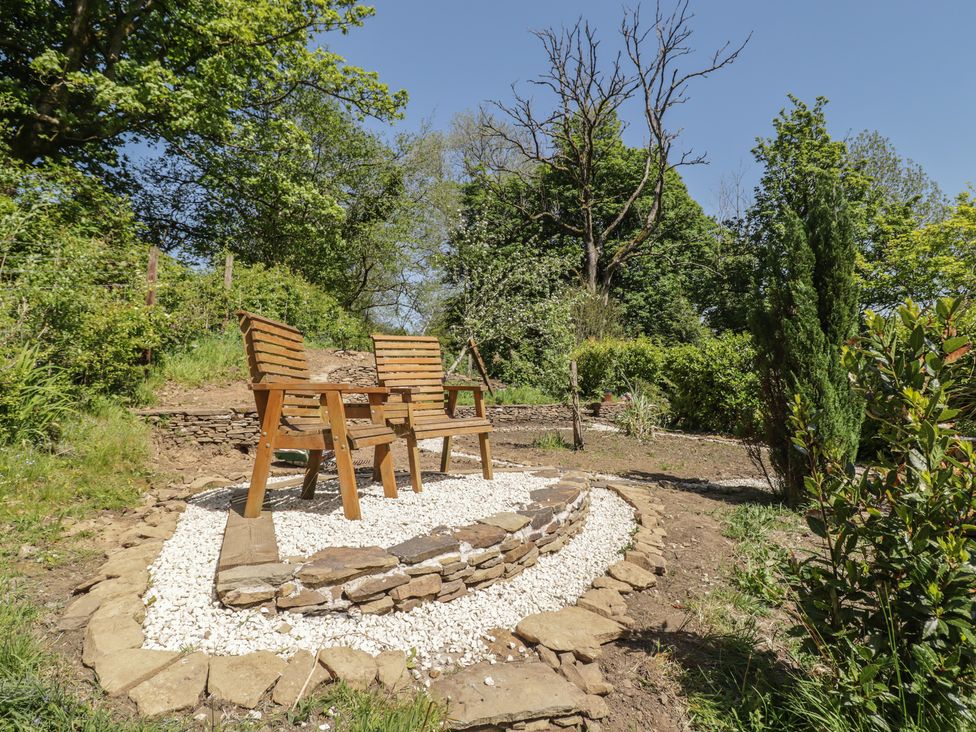 A garden seating area with wooden chairs and a stone path at Cân adar in Llangeinor