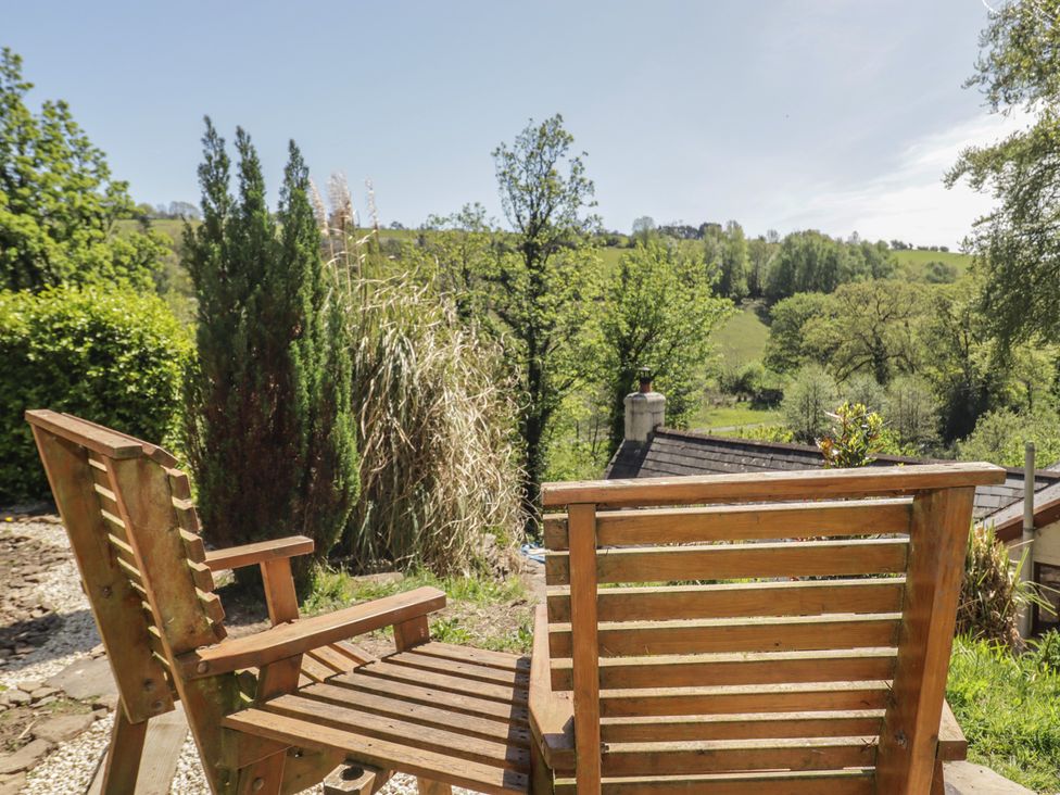 Two wooden chairs facing a view of hills and trees at Cân adar in Llangeinor