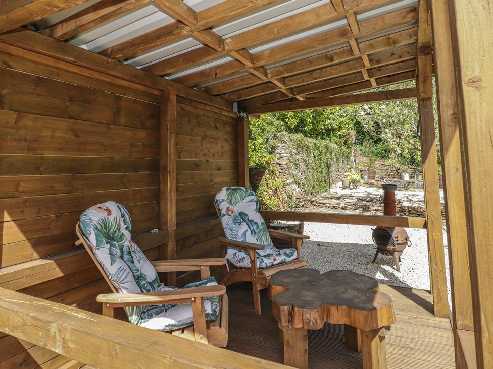 An outdoor seating area with chairs and a wooden table at Cân adar in Llangeinor