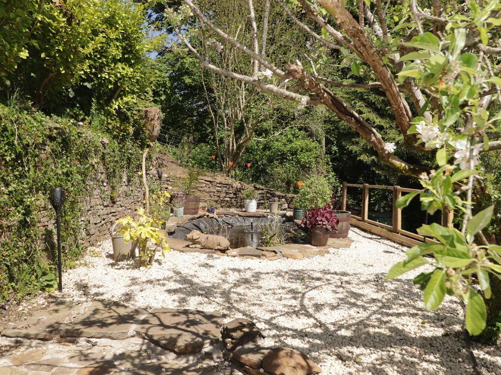 A garden with gravel, plants, and a water feature at Cân adar in Llangeinor