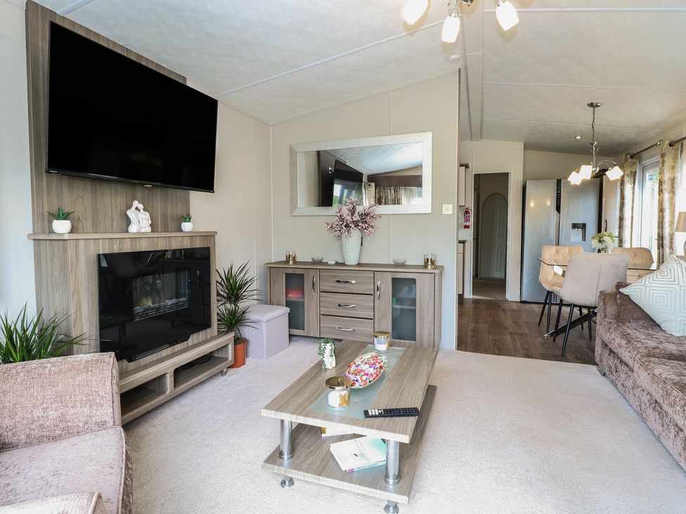 A living room with a television and coffee table at The Norfolk Nook 18 Castle Walk Burgh Castle