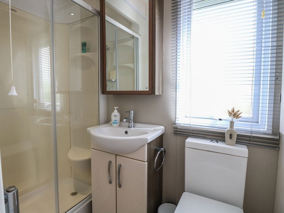 A bathroom with a shower, sink, and toilet at The Norfolk Nook 18 Castle Walk Burgh Castle
