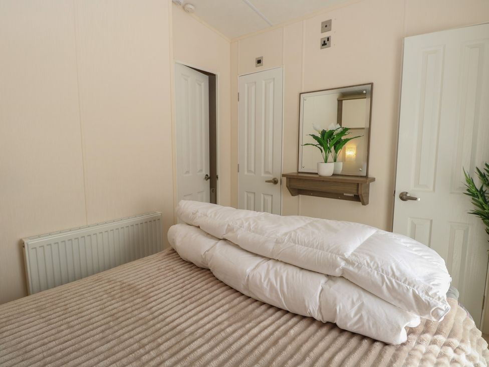 A bedroom with a bed and mirror at The Norfolk Nook 18 Castle Walk Burgh Castle