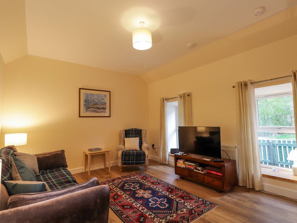 A living room with a sofa and television at Laundry Cottage in Strathpeffer