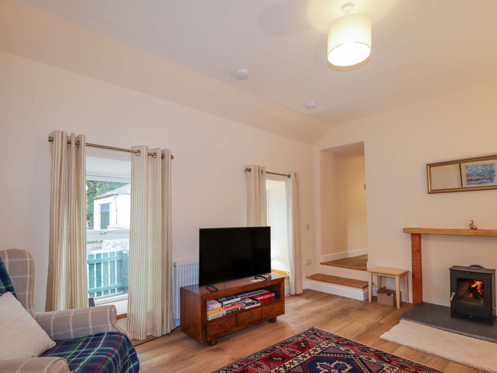 A living room with a television and a fireplace at Laundry Cottage in Strathpeffer