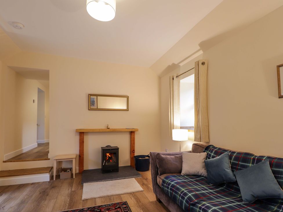 A living room with a sofa and fireplace at Laundry Cottage in Strathpeffer
