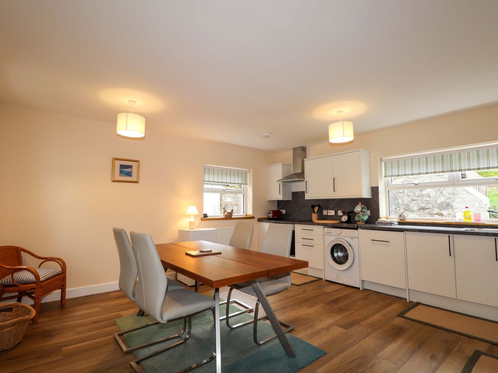 A kitchen with a dining table and appliances at Laundry Cottage in Strathpeffer