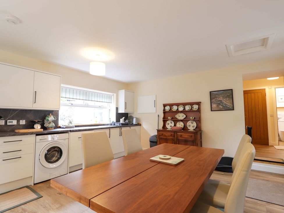 A kitchen with a dining table and washing machine at Laundry Cottage in Strathpeffer