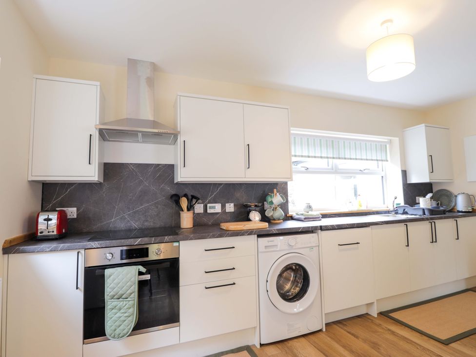 A kitchen with cabinets and appliances at Laundry Cottage in Strathpeffer