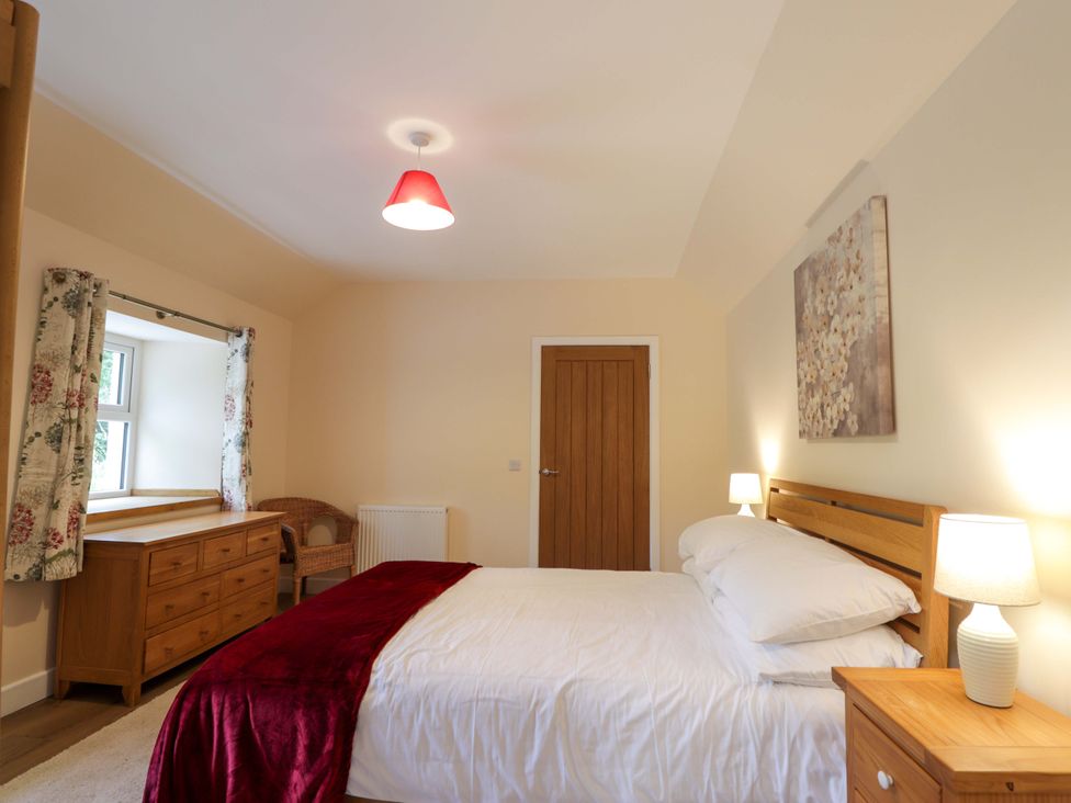 A bedroom with a bed and dresser at Laundry Cottage in Strathpeffer