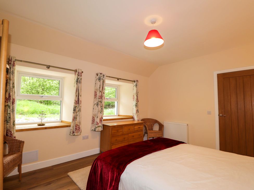 A bedroom with two windows and a dresser at Laundry Cottage in Strathpeffer
