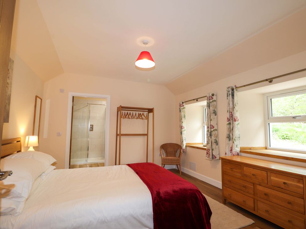 A bedroom with a bed and a wardrobe at Laundry Cottage in Strathpeffer