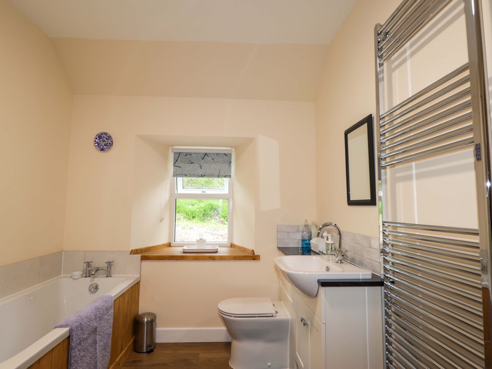 A bathroom with a bath tub and sink at Laundry Cottage in Strathpeffer
