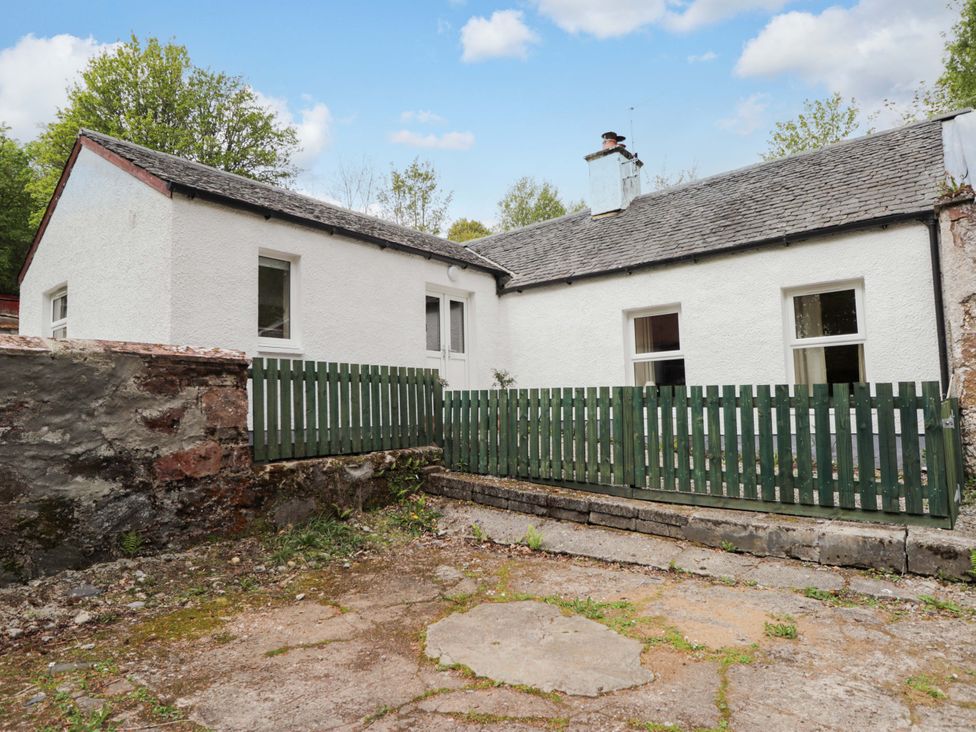 A house with a green fence and chimney at Laundry Cottage in Strathpeffer