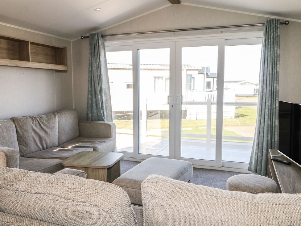 A living room with sofa and sliding door at Seaside Retreat in Selsey