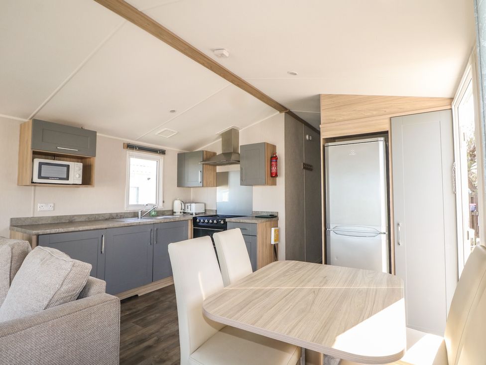 A kitchen with appliances and dining area at Seaside Retreat in Selsey
