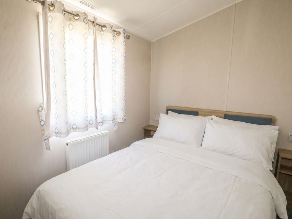 A bedroom with a bed and curtains at Seaside Retreat in Selsey