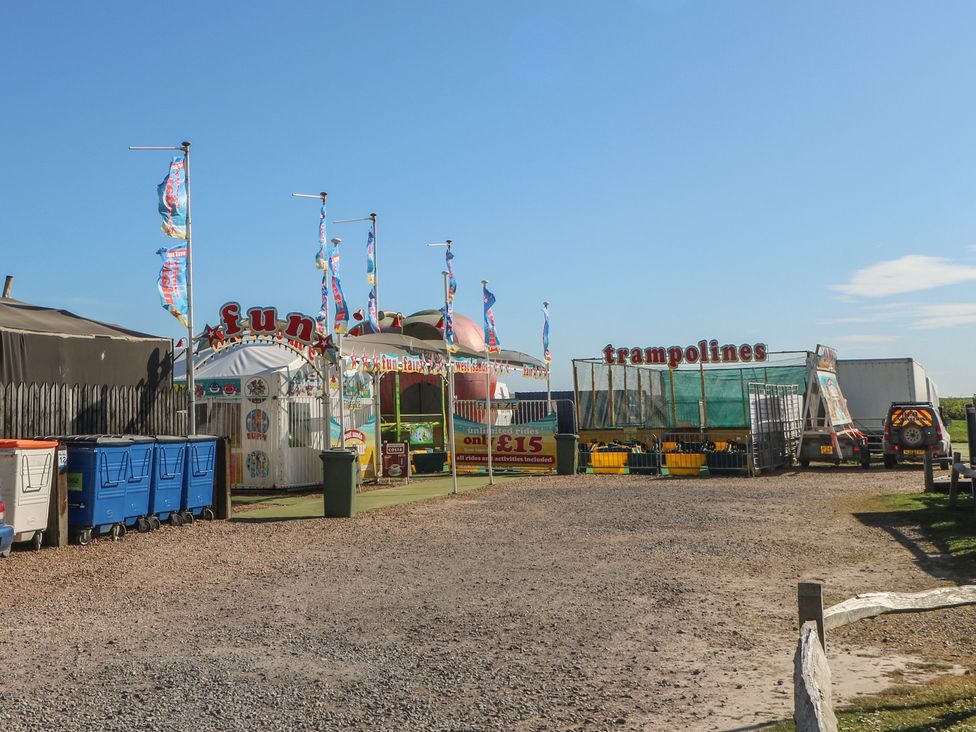 An outdoor amusement area with trampolines and funfair tents at Seaside Retreat in Selsey