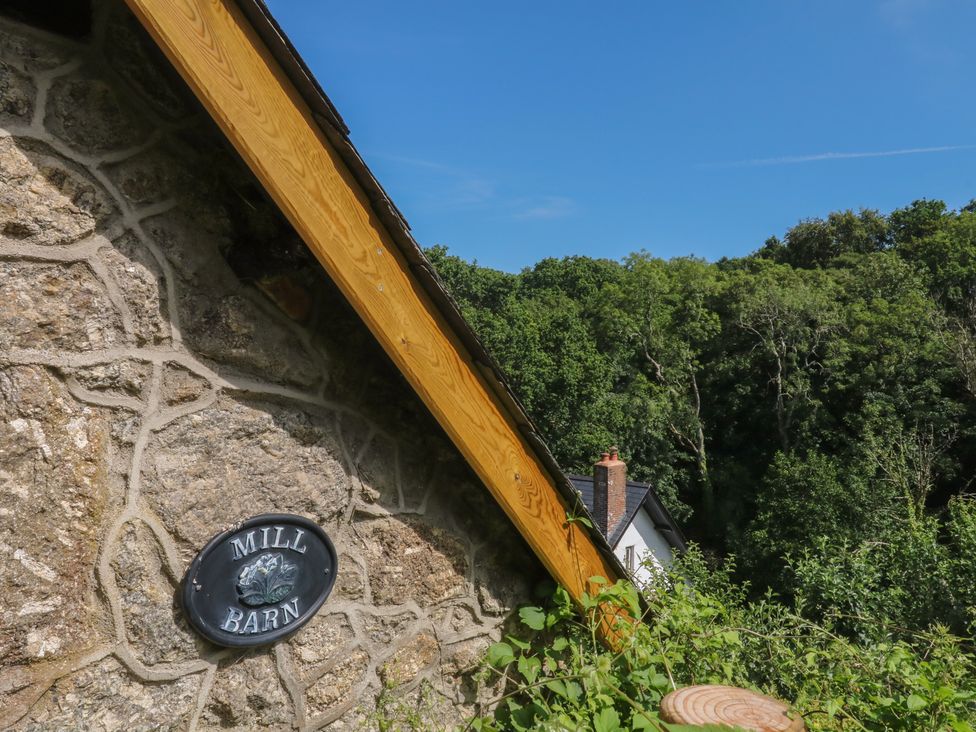 A roof with a stone wall and sign at The Mill Barn in Lustleigh