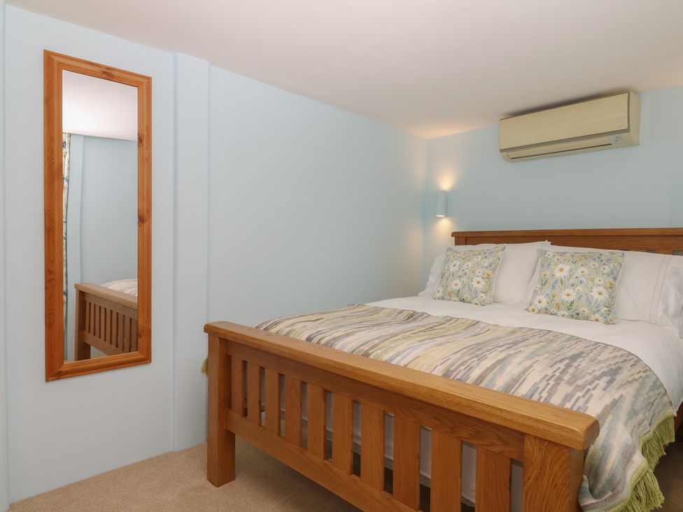 A bedroom with a bed and a mirror at The Mill Barn in Lustleigh