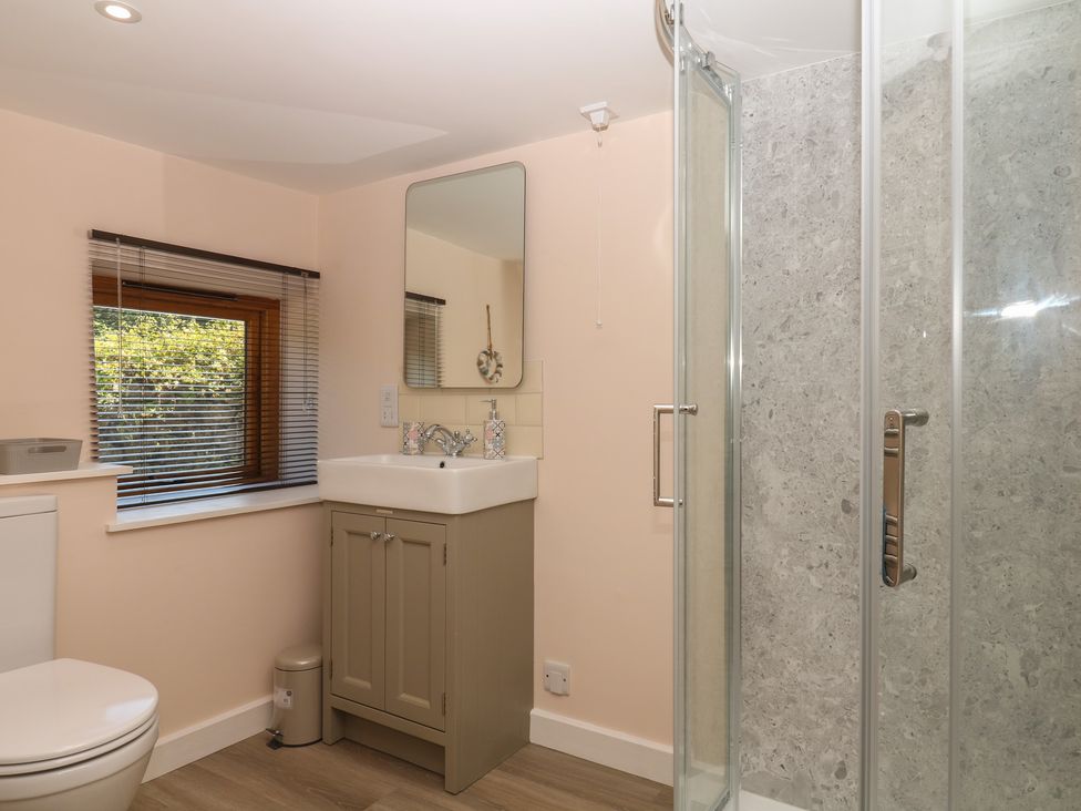 A bathroom with a sink, toilet, and shower at The Mill Barn in Lustleigh