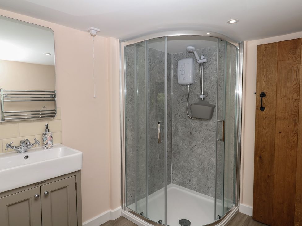 A bathroom with a sink, shower, and mirror at The Mill Barn in Lustleigh