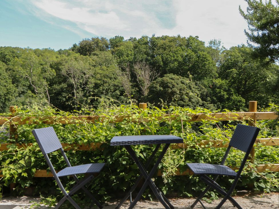 A table and chairs on a patio surrounded by greenery at The Mill Barn in Lustleigh