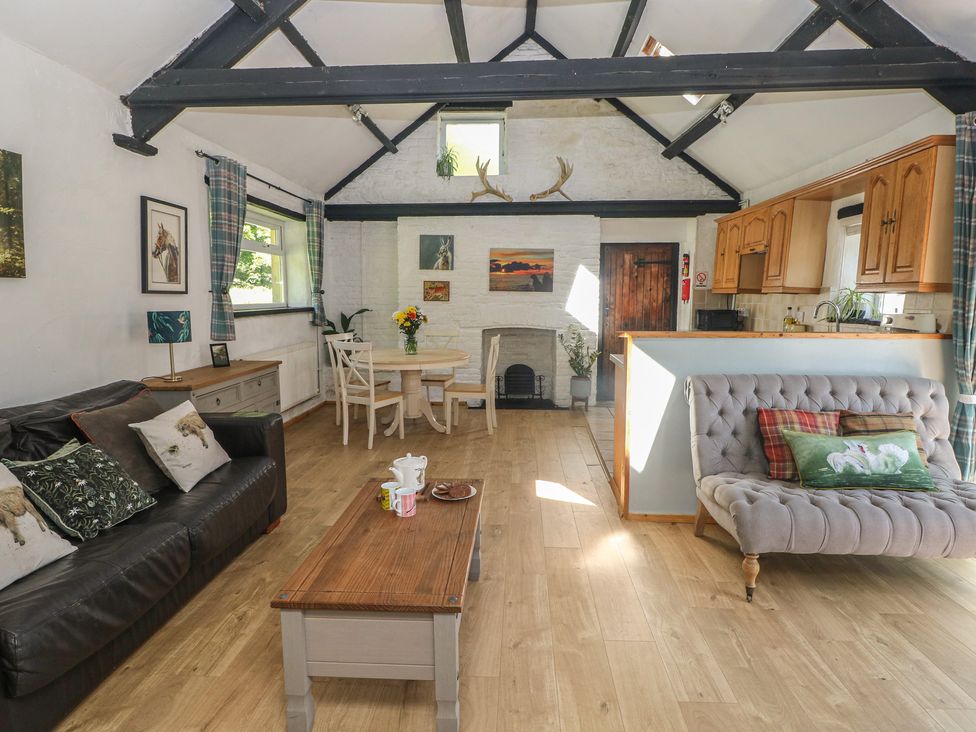 A living room with a dining area and kitchen cabinets at Daffodil Cottage in Blaencwm near Treorchy