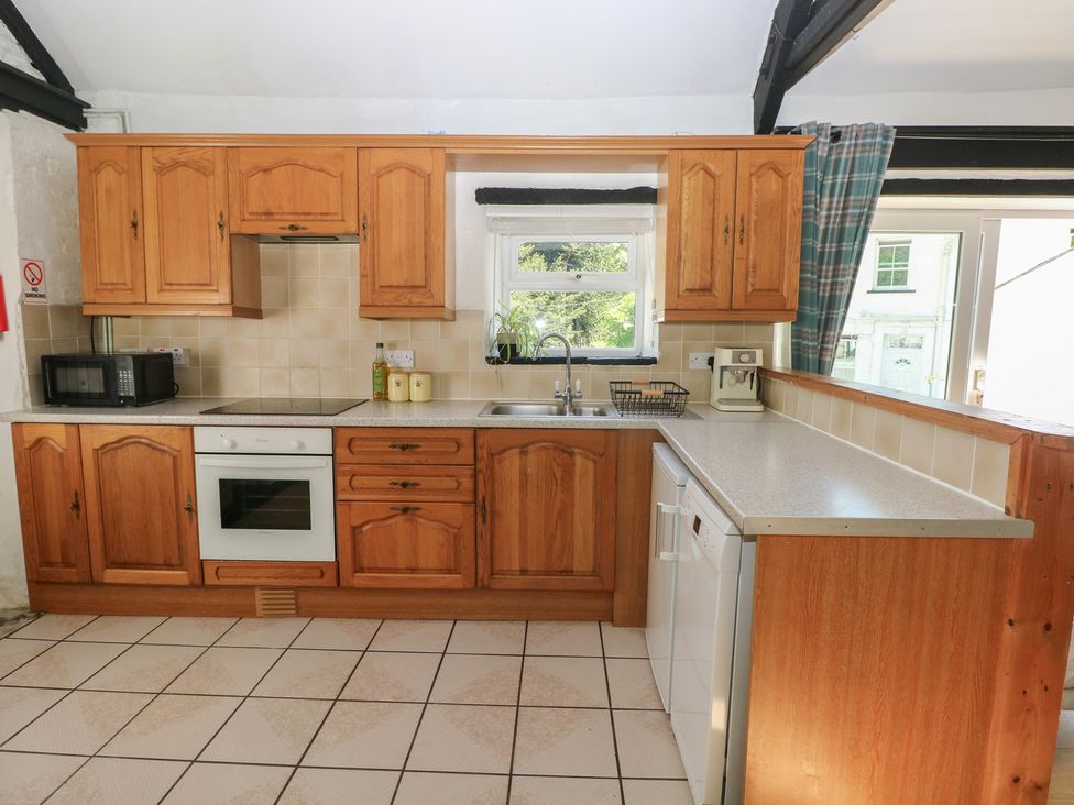 A kitchen with wooden cabinets and appliances at Daffodil Cottage in Blaencwm near Treorchy