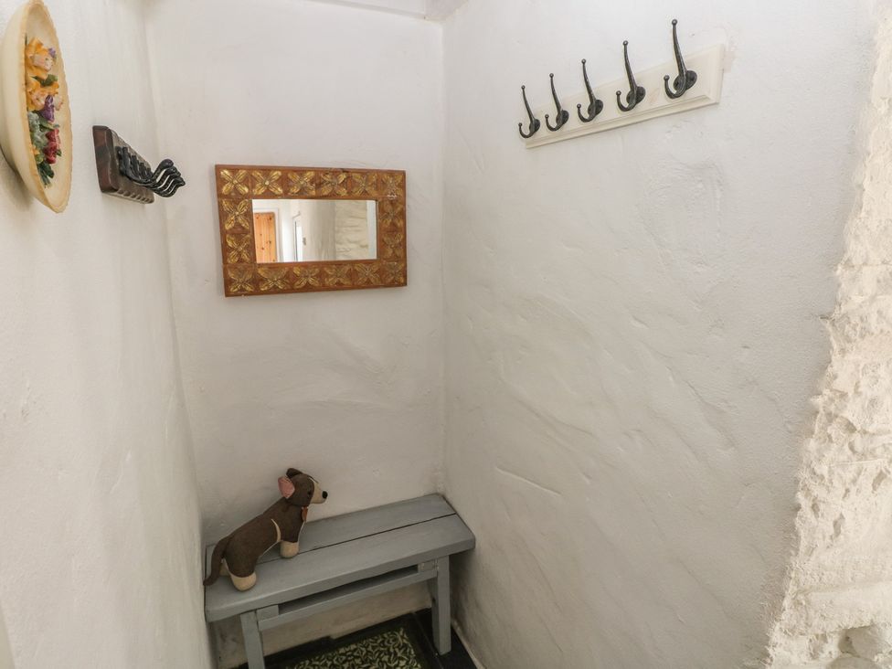 A hallway with a mirror, hooks, and a bench at Daffodil Cottage in Blaencwm near Treorchy
