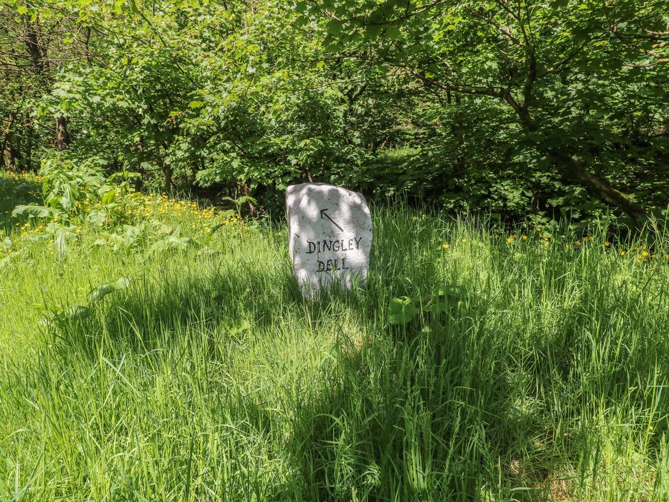 A stone sign marking Dingley Dell in a wooded area