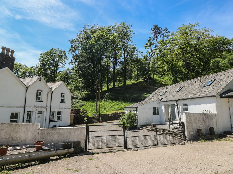 An outdoor view of houses with a gate and trees at Daffodil Cottage in Blaencwm near Treorchy