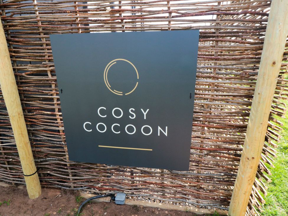 A sign for Cosy Cocoon next to a wooden fence