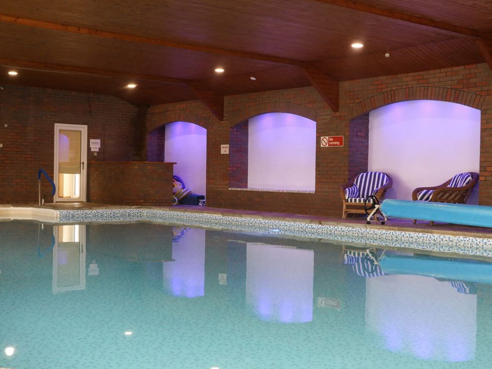 An indoor pool area with loungers and a brick wall at Cosy Cocoon in Malton