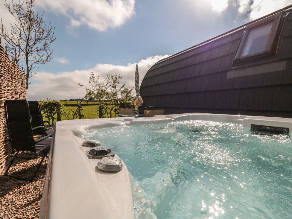 A hot tub beside deck chairs at Natures Nest in Malton
