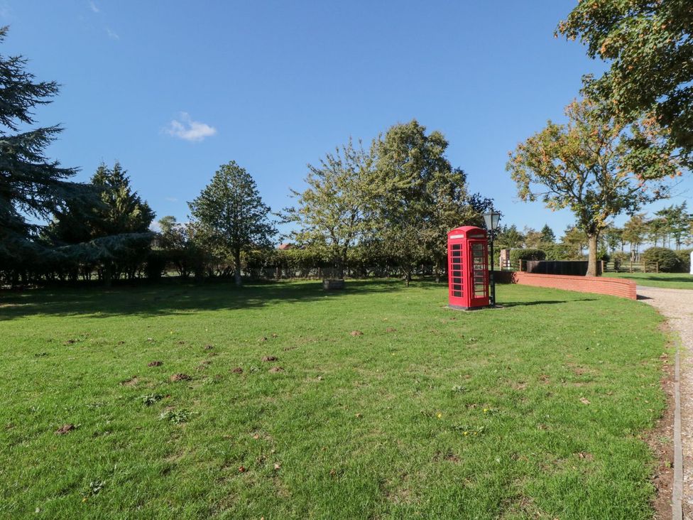 An outdoor area with a red telephone box and trees at Natures Nest in Malton