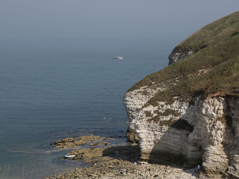 A rocky shore with people and a boat at Natures Nest in Malton