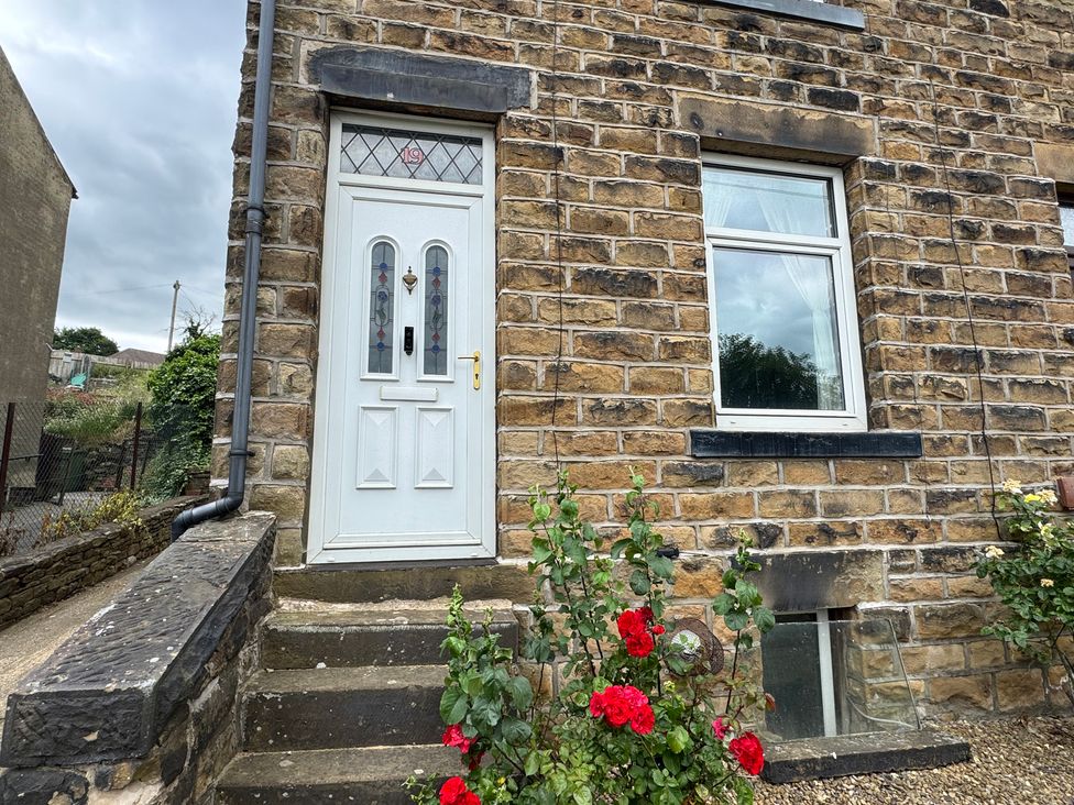 A front door and window on a brick wall with flowers at Herbert Terrace in Dewsbury