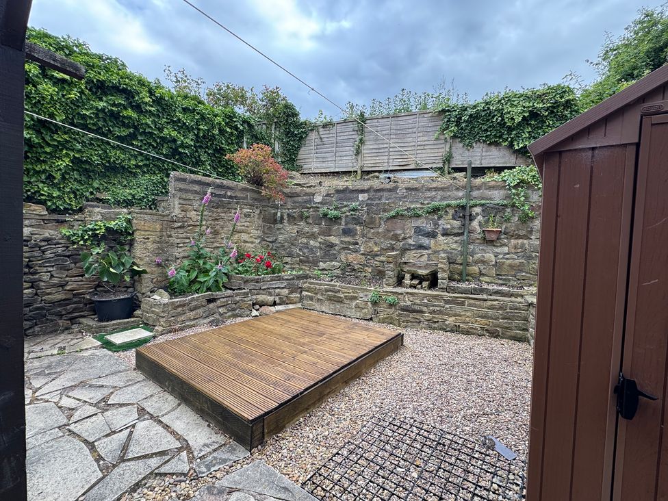 A garden with a wooden deck and stone walls at Herbert Terrace Dewsbury