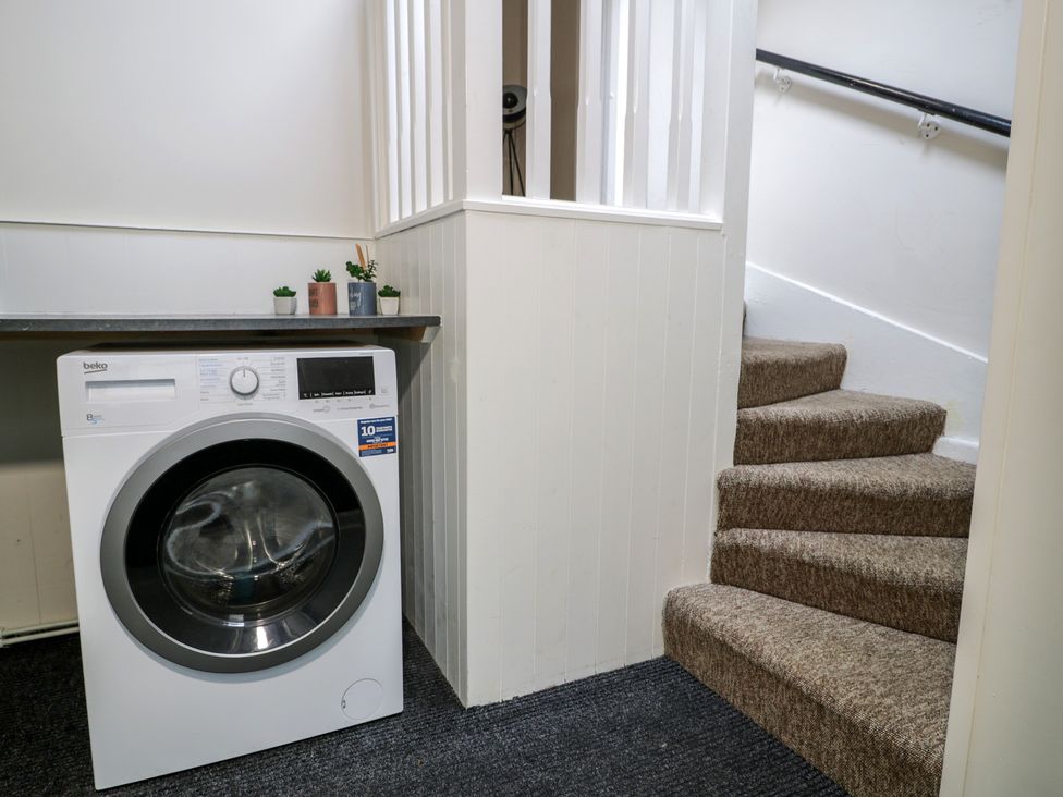 A utility room with a washing machine and stairs at Llety Cllyd in Barmouth