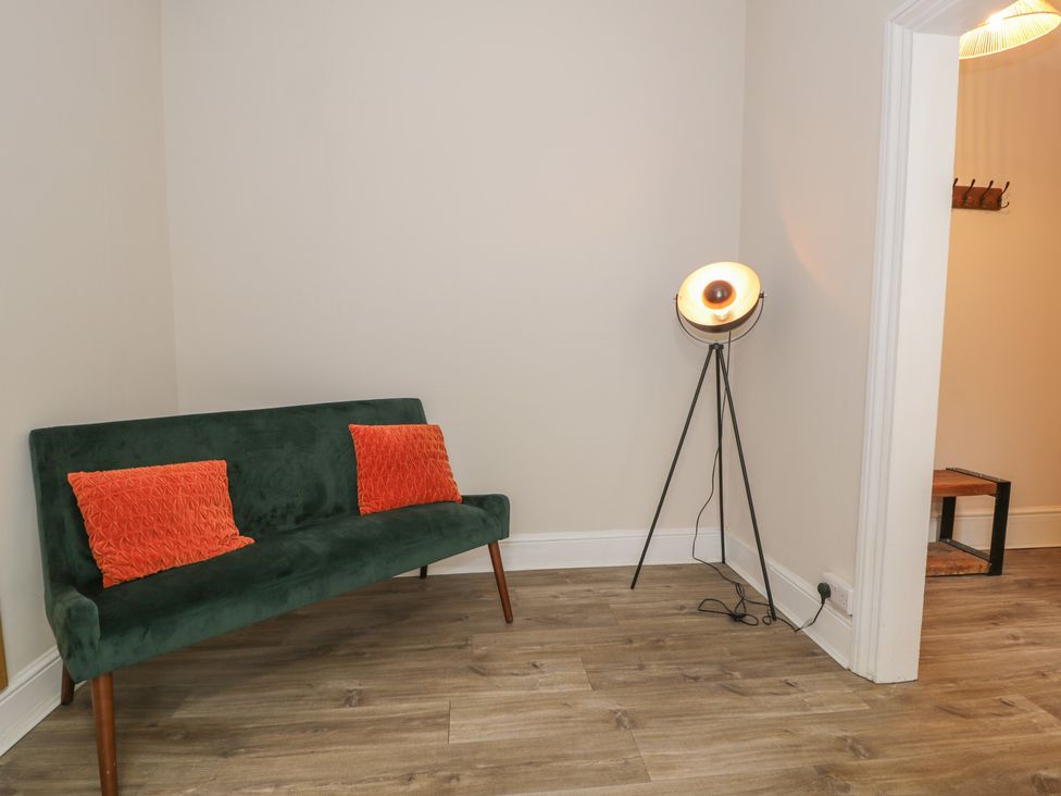 A living room with a green sofa and a floor lamp at Llety Cllyd in Barmouth