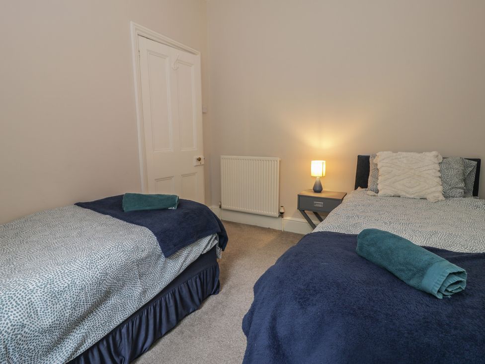 A bedroom with two beds and a bedside table at Llety Cllyd in Barmouth