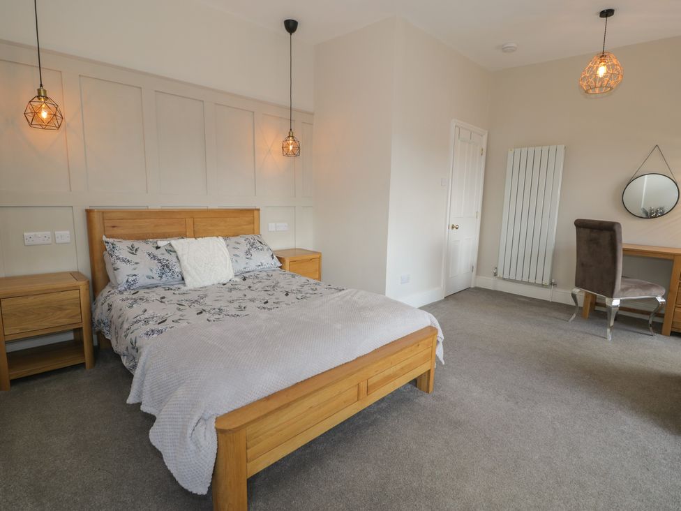 A bedroom with a bed, nightstand, desk and chair at Llety Cllyd in Barmouth