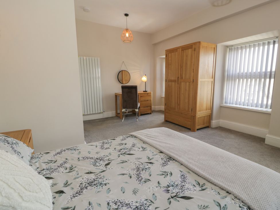 A bedroom with a bed, wardrobe, desk, and chair at Llety Cllyd in Barmouth