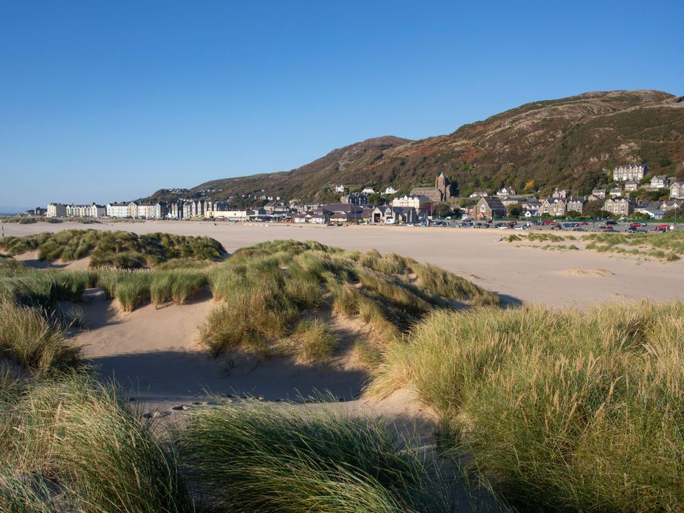 A beach view with dunes and nearby buildings at Llety Cllyd in Barmouth
