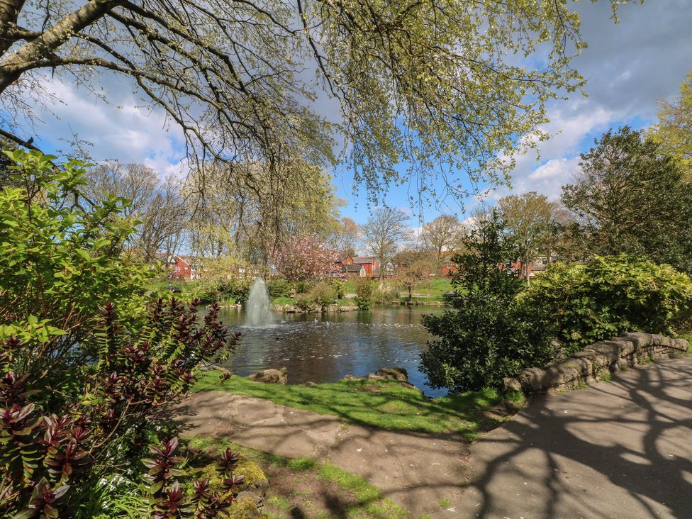 A park with a fountain and blooming trees near water at Apartment 3 Lytham St. Annes