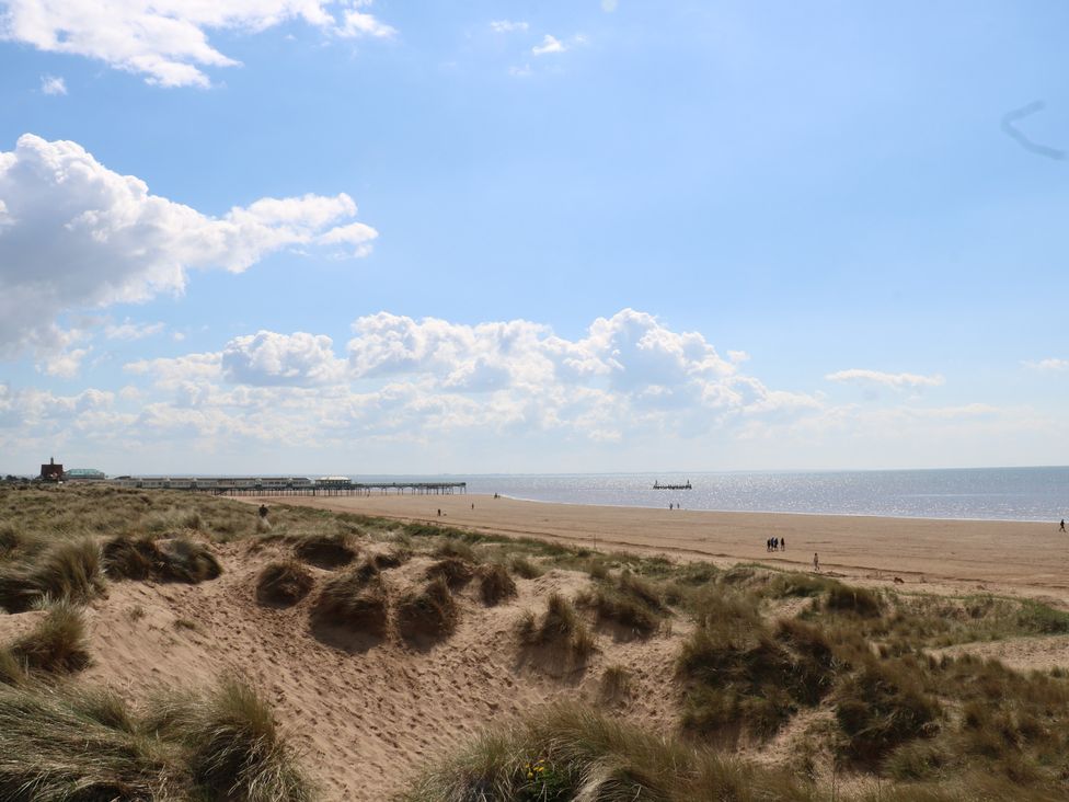 A beach with sand dunes and a pier at Lytham St. Annes