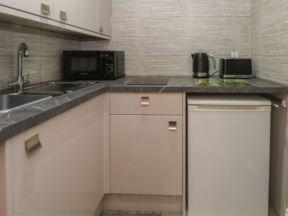 A kitchen with a sink, microwave, kettle, toaster, and fridge at Apartment 4 in Lytham St. Annes