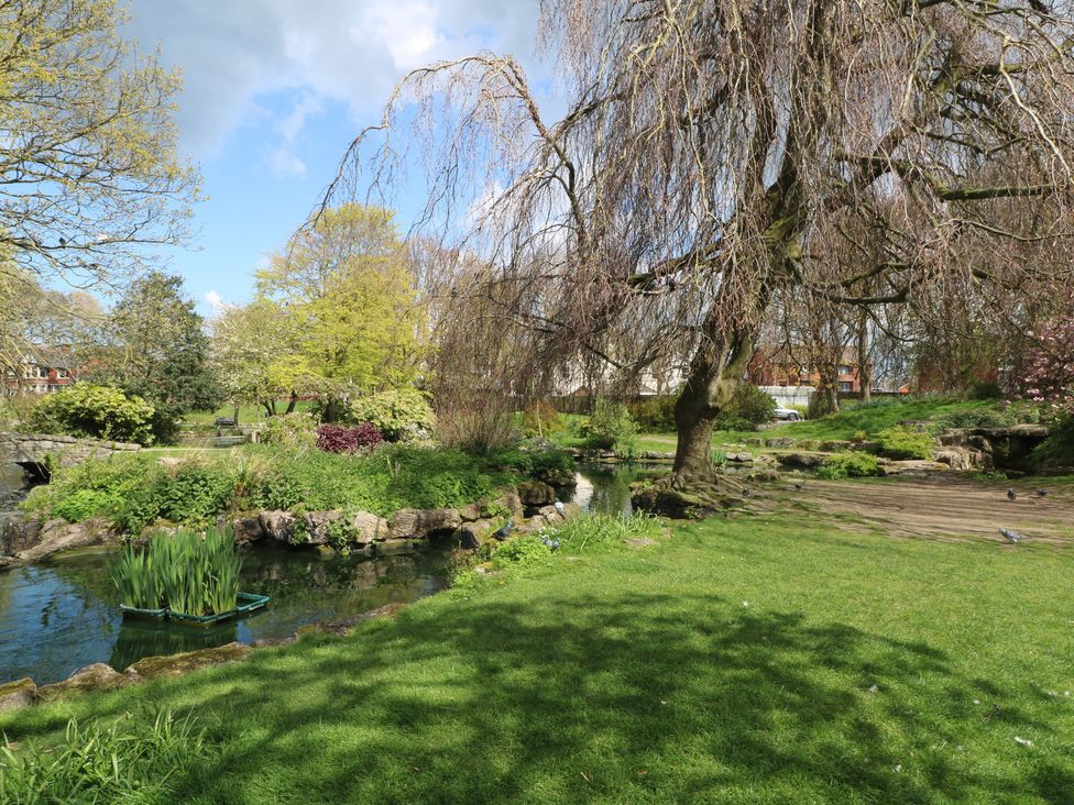 A garden with a pond and trees at Apartment 4 in Lytham St. Annes
